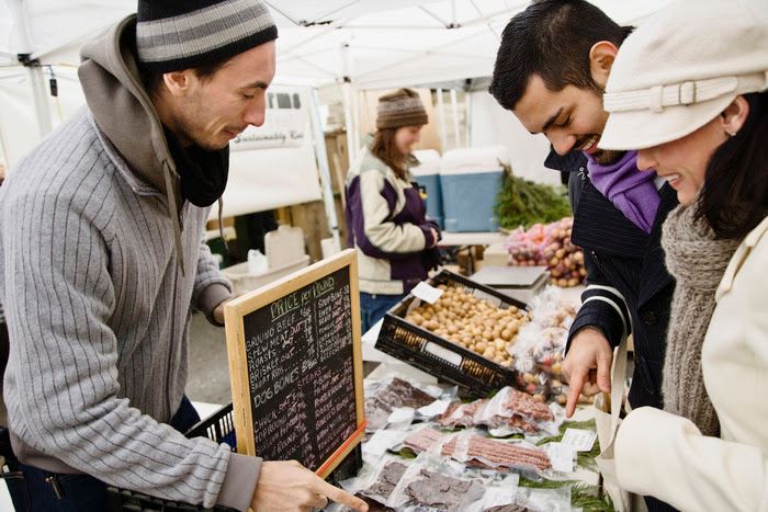 This is a photo of two shoppers looking at food being sold at a Farmer's Market.